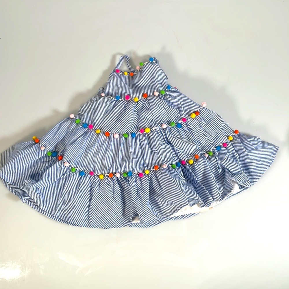 Blue and white striped dress with colorful pom poms.